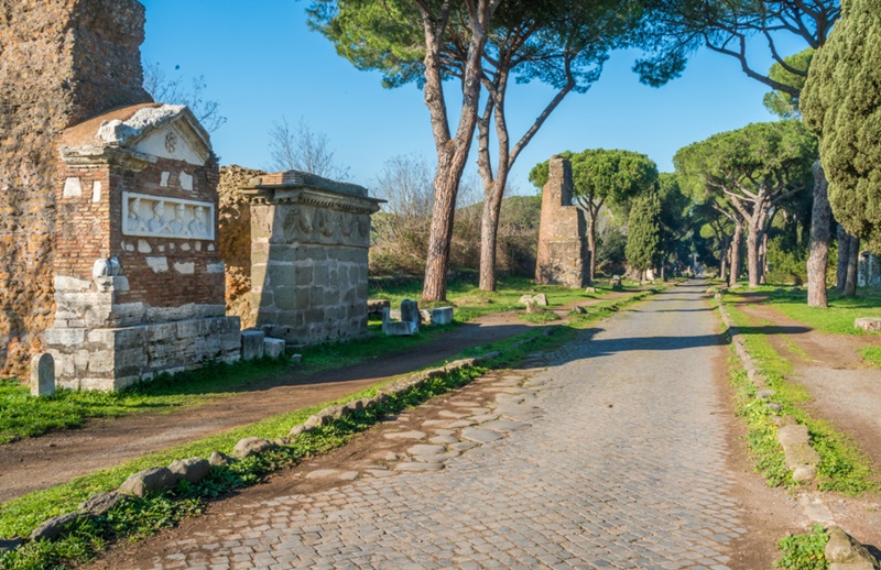 Pequeno grupo de turistas caminhando com guia por ruínas romanas